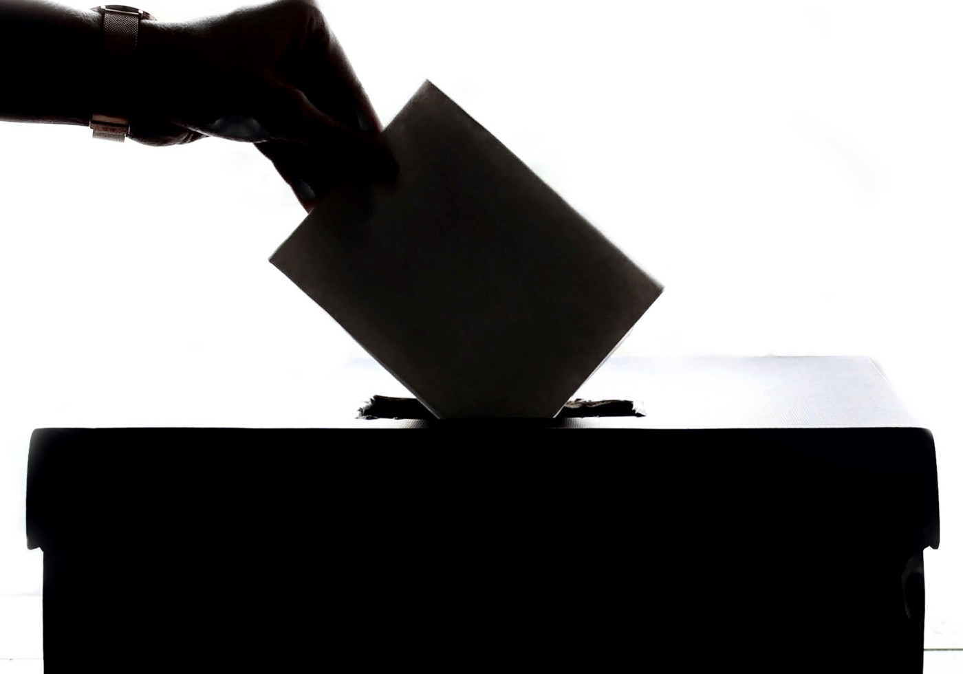 Silhouette of ballot being dropped into a ballot box.